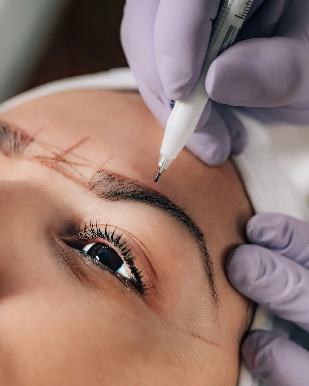 Microblading kalemiyle kasa tel tel uygulama yapan eldivenli eller